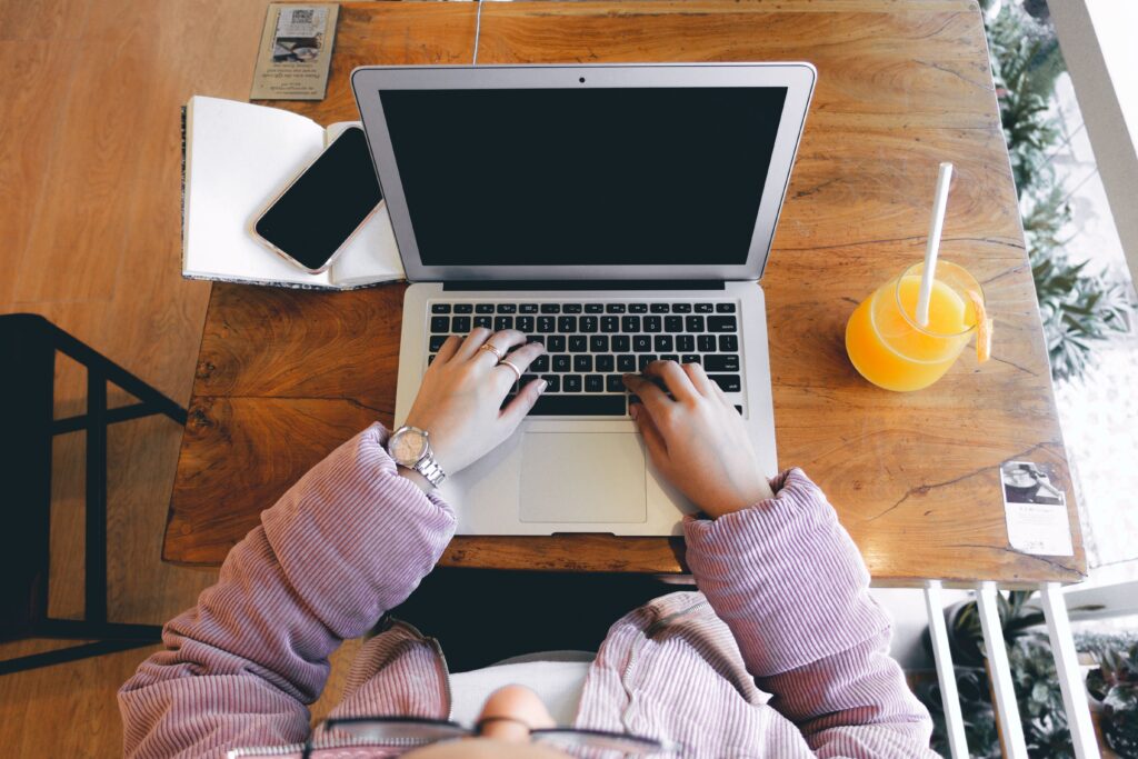 Persona trabajando en su laptop desde una cafetería mientras gestiona su negocio