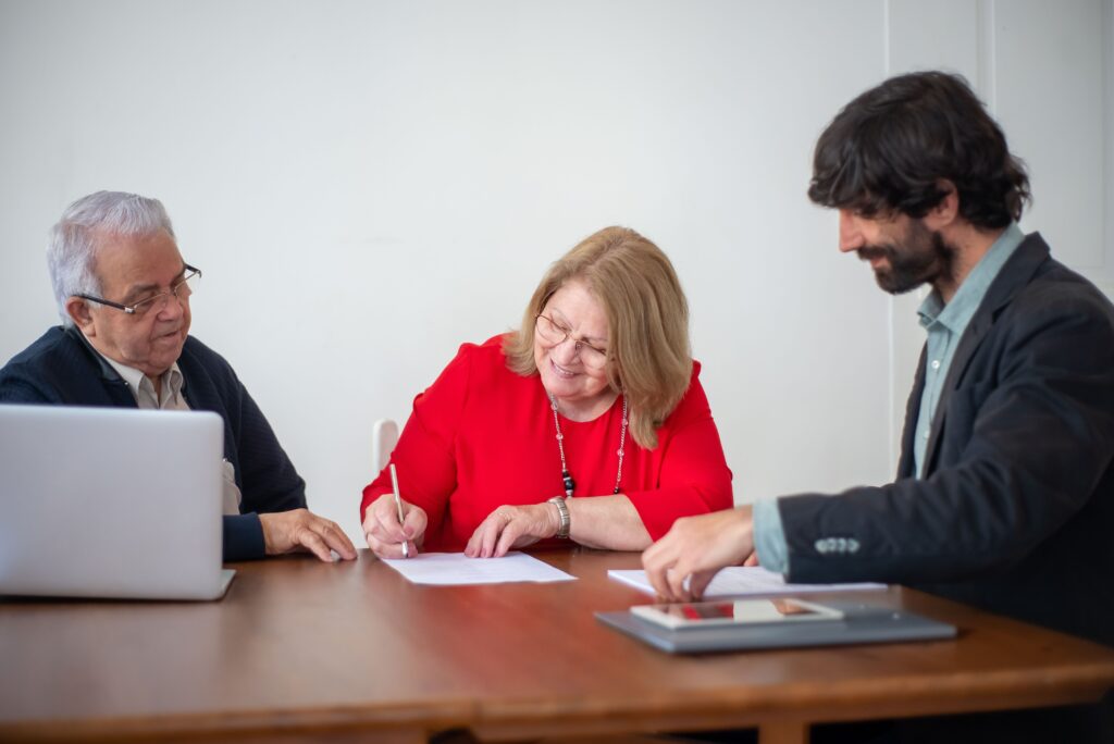 : Familia hispana firmando contrato de compra de vivienda con agente inmobiliario