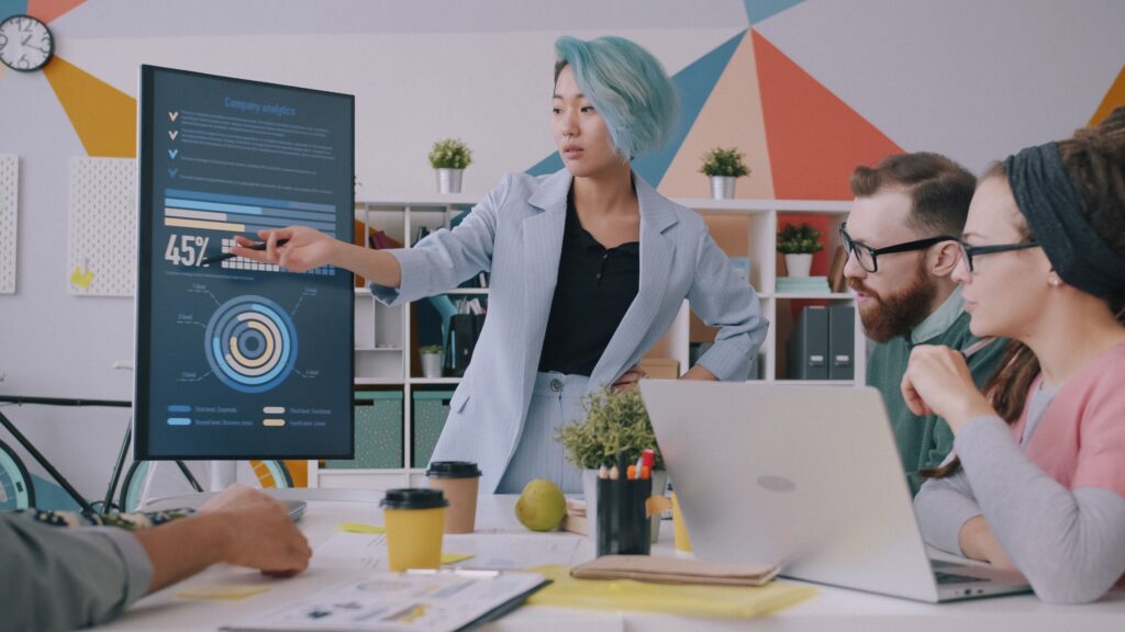 Equipo revisando estadísticas de su negocio en una pantalla con gráficos