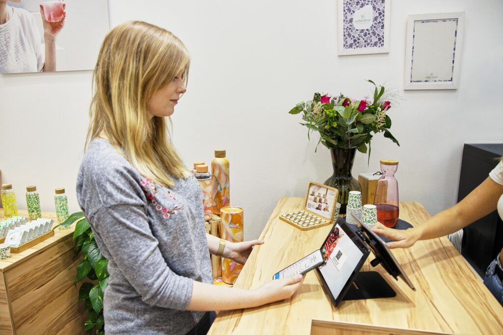 Dueña de un negocio atendiendo a una clienta en el mostrador con una tablet