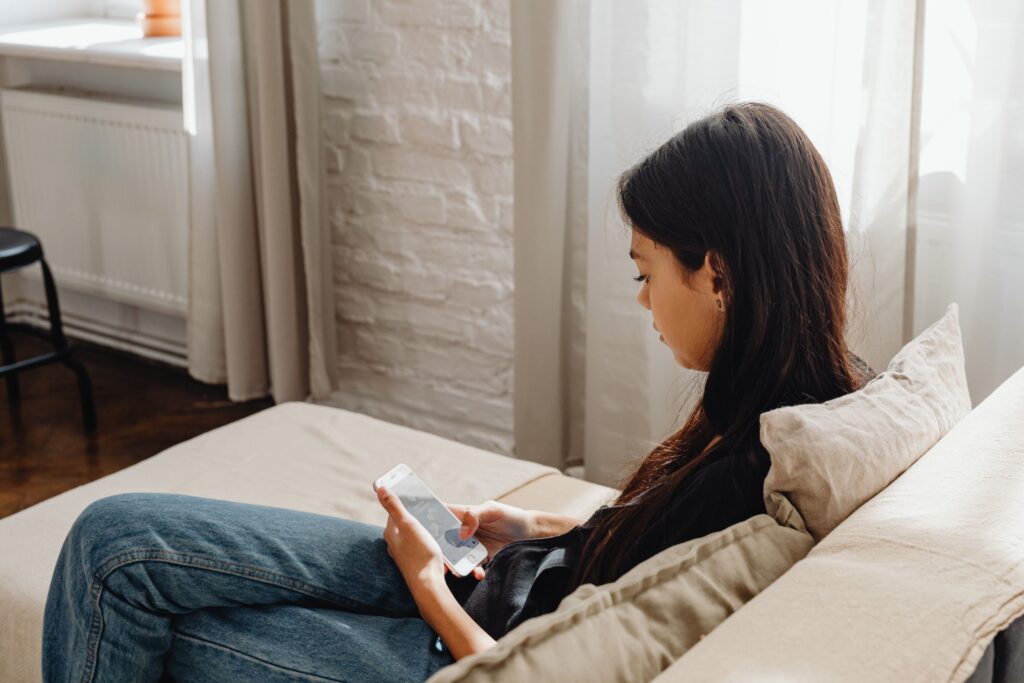 Persona sentada en un sillón revisando notificaciones en su celular, representando el remarketing que recuerda a un cliente sobre un producto que vio.